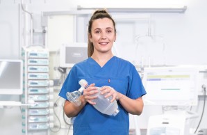 Intensivpflegerin in einem weißen Raum hält ein medizinsches Gerät