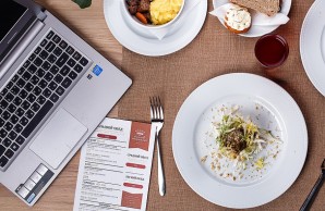 Ein Teller und Schalen mit Essen stehen neben einem Laptop