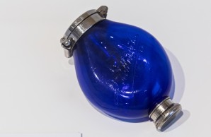 Ein tiefblaues Gläsfläschen mit Verschluss, das Spuckfläschenchen -Blauer Heinrich- erklärt der Text im Schaukasten