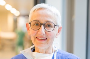 Ulrike Heidelbach, Intensivpflegerin lächelt in die Kamera, graue kurze Haare, auffällige Brille mit rundem Gläsern, offener direkter Blick