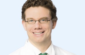 Ein Porträt-Foto. Prof Huber blickt lächelnd in die Kamera, er trägt eine Brille mit dunklem kleinen Metallgestell.