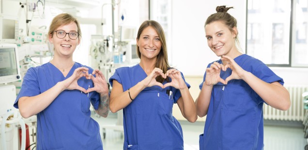 Drei Pflegende der Intensivstation zeigen das Herz-Symbol mit ihren Händen
