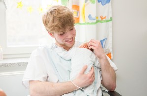 Auszubildender der Krankenpflege hält Kind im Arm
